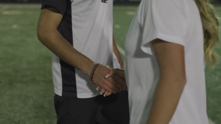 A man and a woman on a sports field shaking hands