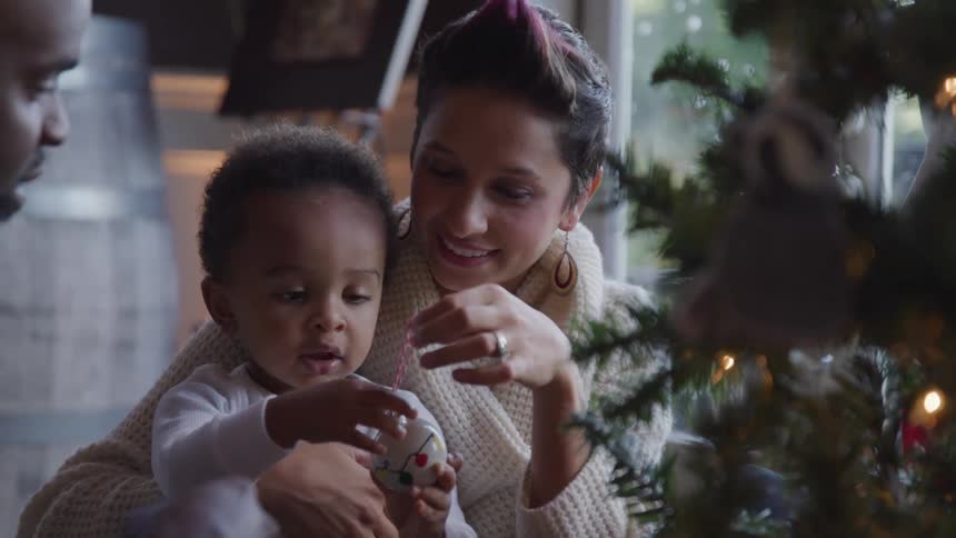 Parents playing with their baby close to a christmas tree