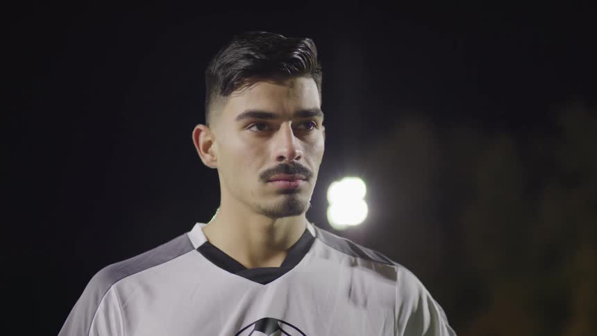 A man in a football uniform standing and looking off into the distance