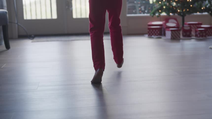 Child runs across floor toward presents under christmas tree