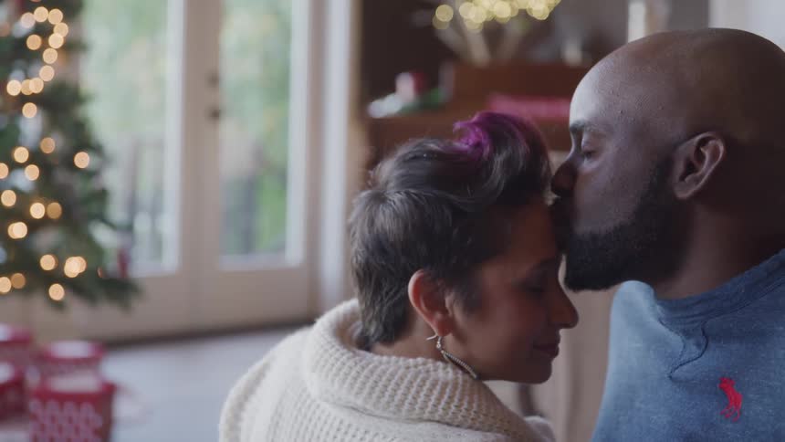 A couple has a romantic moment in their home during the christmas holiday