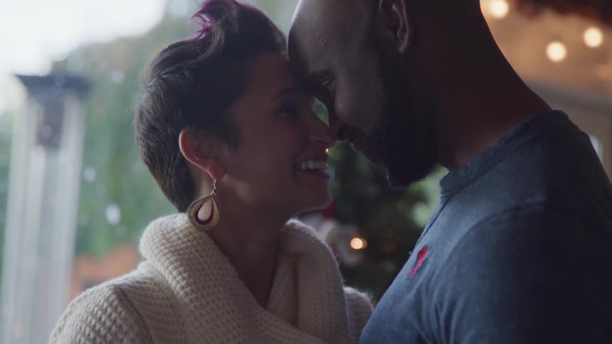 Couple dancing together inside their house while touching their heads in a romantic way