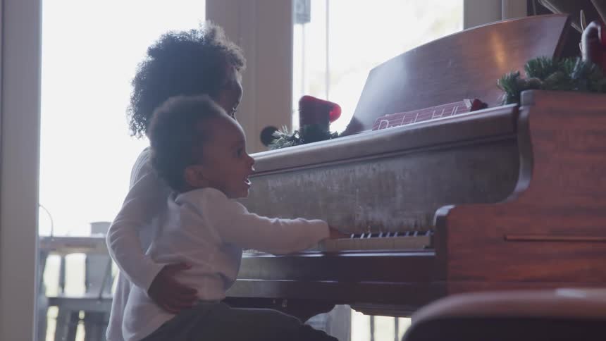 Two black children play on the piano