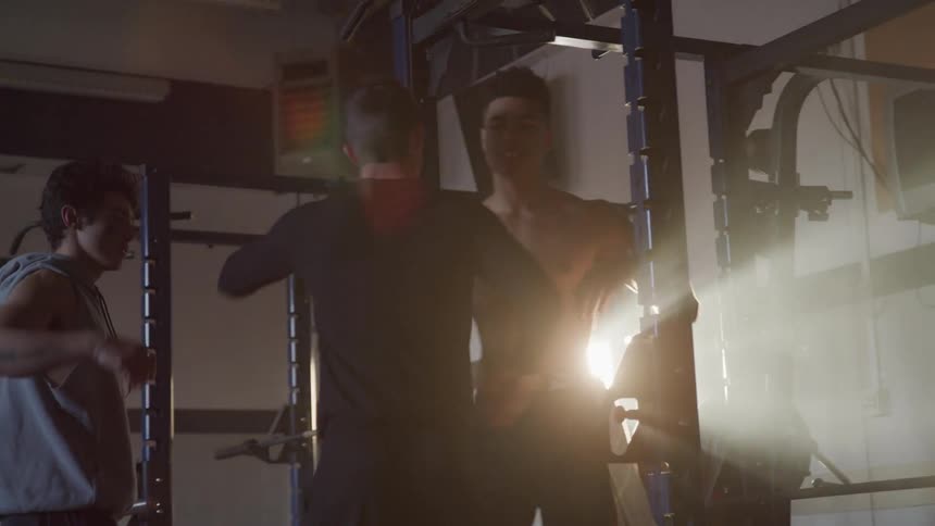 Three men greet each other in a gym and hug and shake hands