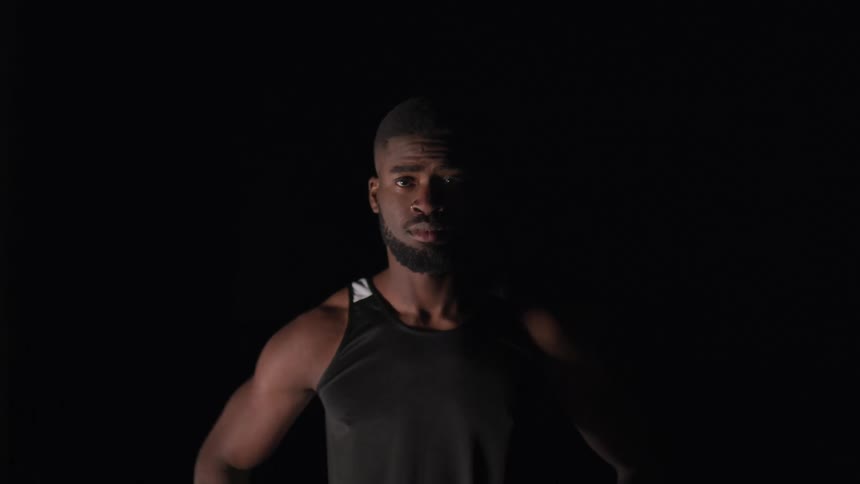 Man wearing tank top stands looking down before looking straight ahead