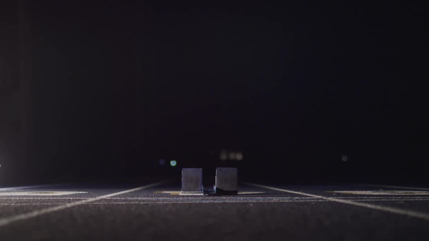 A starting line in a running track at nighttime