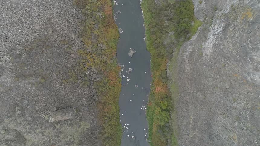 Boats sit in the narrow river that runs between the mountains