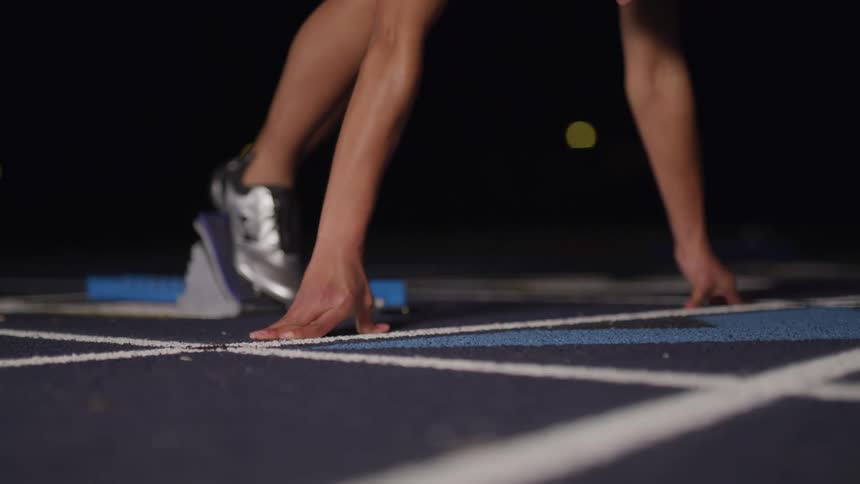 Person starts running from starting block at night