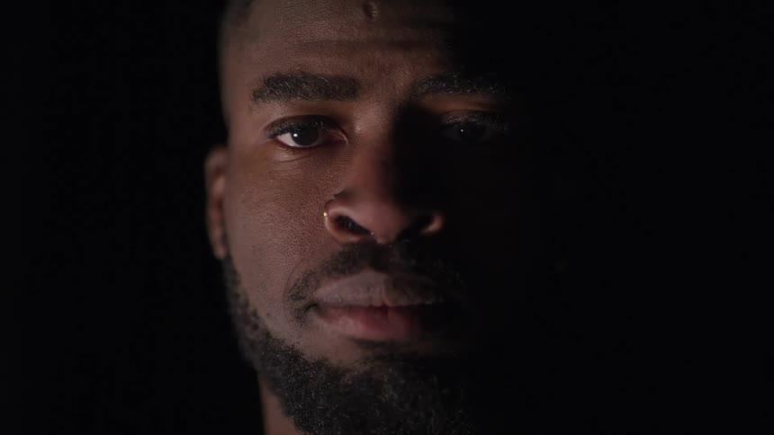 Bearded black man raises his head and looks at the camera on the background