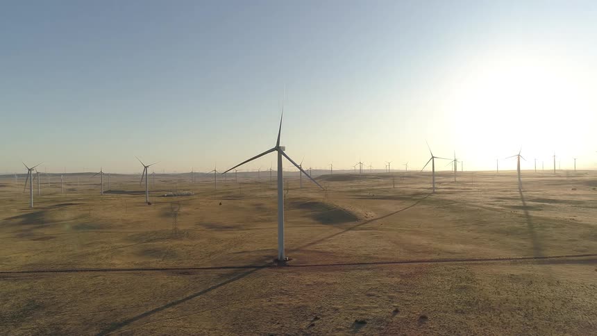 A wind turbine farm with the sky in the background