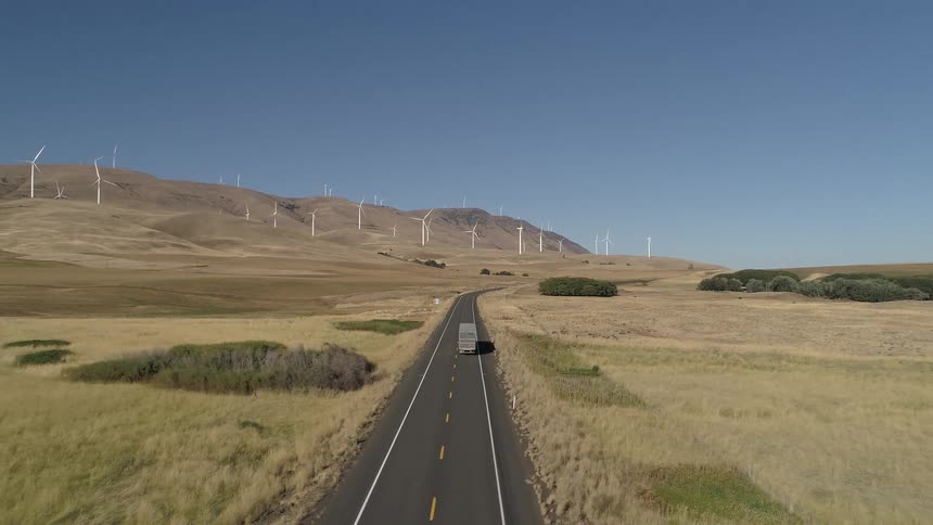 A bus traveling a long country road through a grassland
