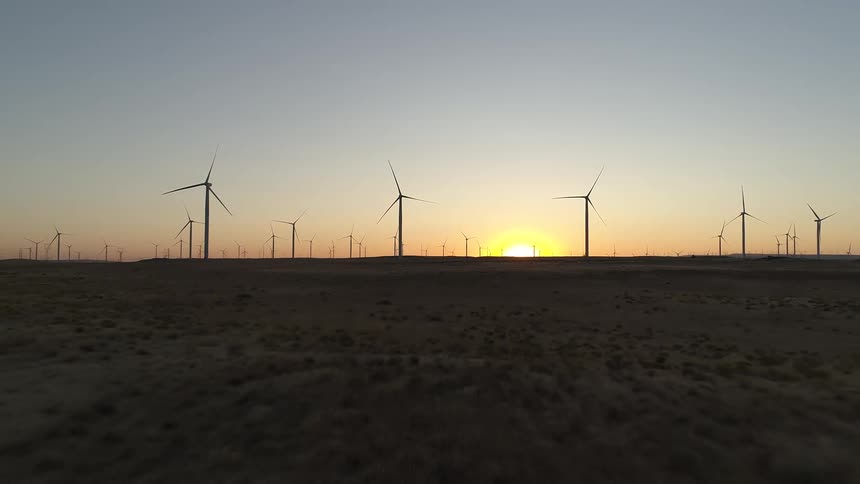 A wind turbine farm with the sky in the background