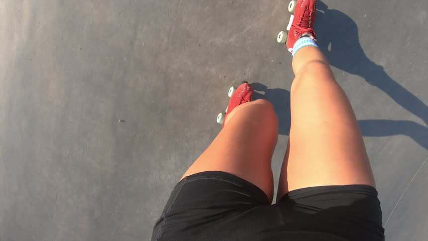 A woman roller skates at an outdoor skate park on a sunny day
