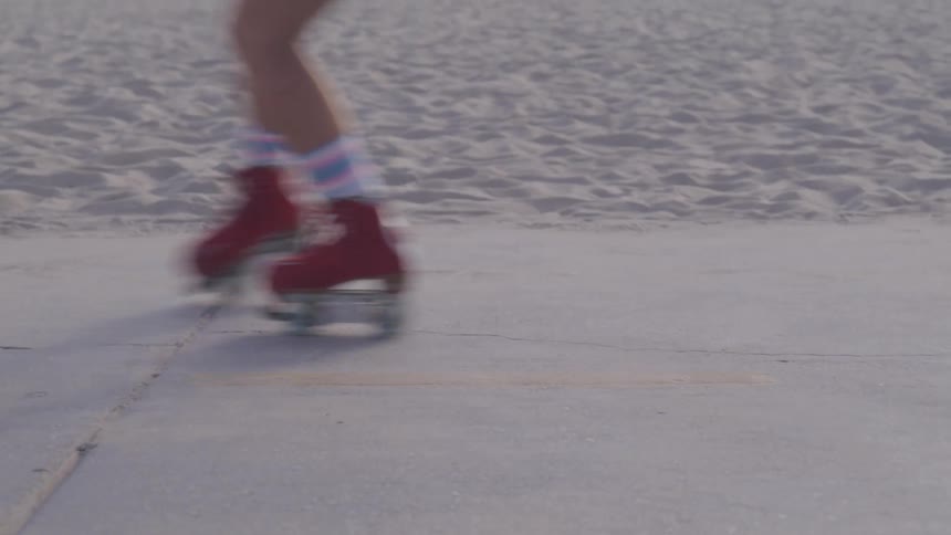 Young person skating on a sidewalk in front of a beach