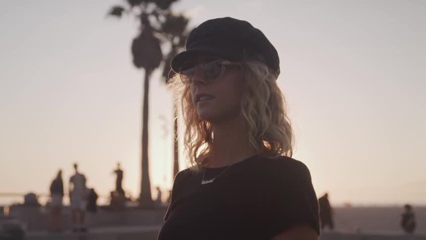 A woman stands outside with others watching the sun set