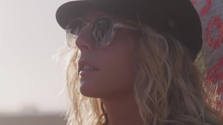 A woman in a hat and sunglasses standing outside and gazing upwards