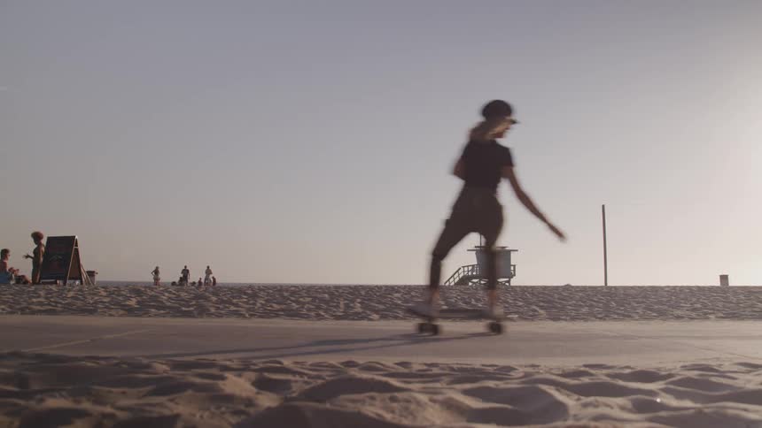 White woman skating through a sidewalk in front of a beach