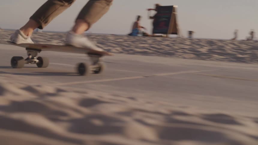Person skating through a sidewalk in the middle of the beach