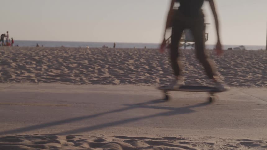 Skateboarder rides a skateboard on a path near the beach