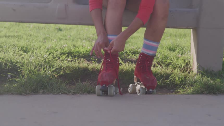 A woman ties her roller skates and rides off