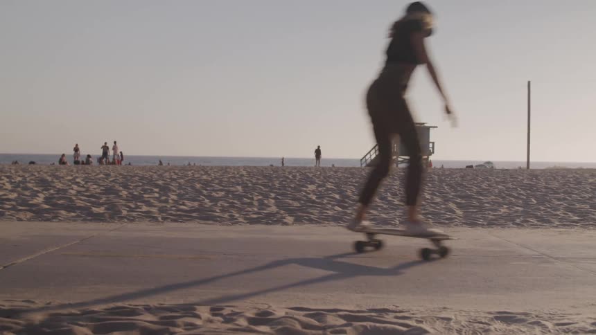 A woman skateboarding along a path near a beach during the day