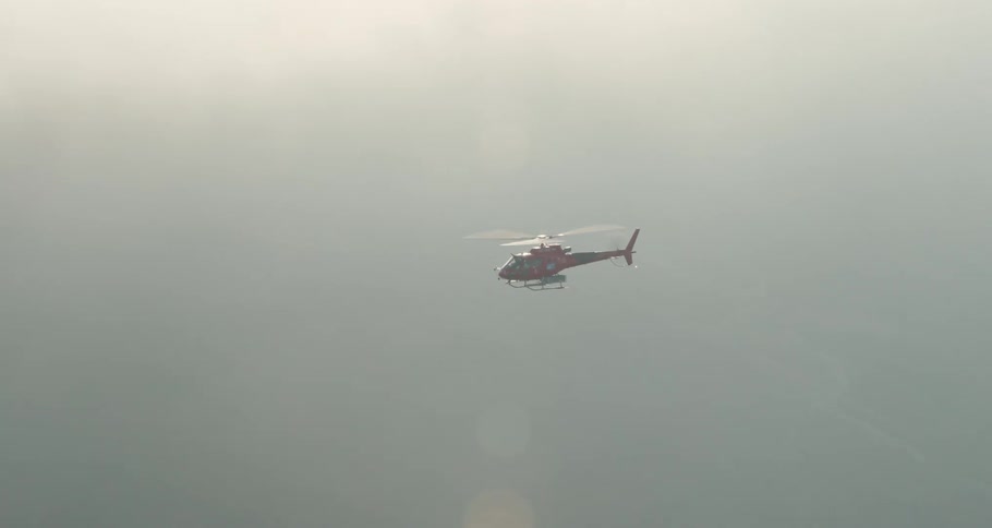 Helicopter flies through fog obscuring forest