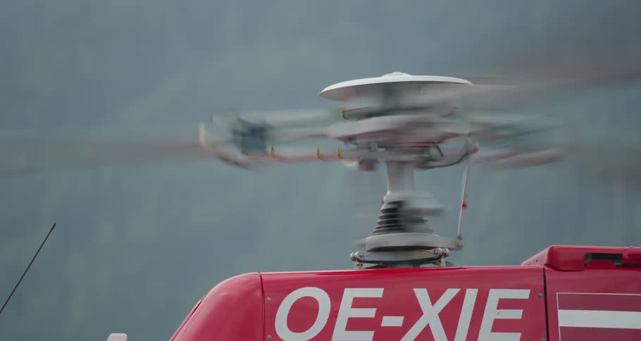 Helicopter blades spin and rotate as the helicopter is parked near trees