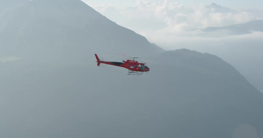 Red helicopter hovers near the mountains