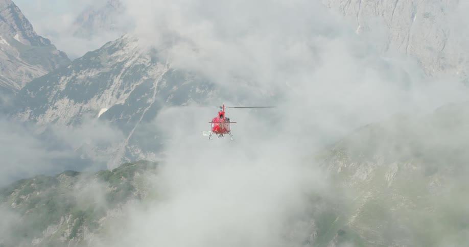 A helicopter flying through the clouds above a mountain