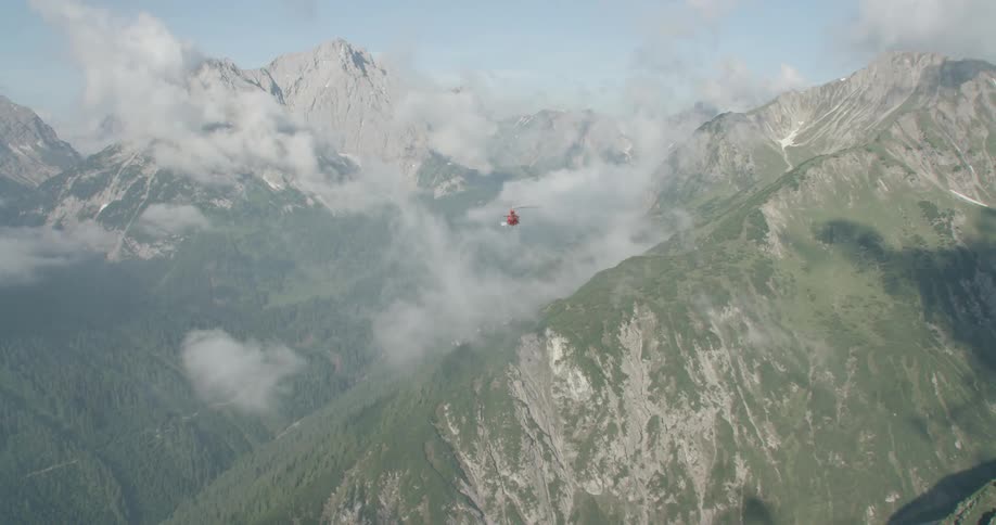 The helicopter flies near the mountains