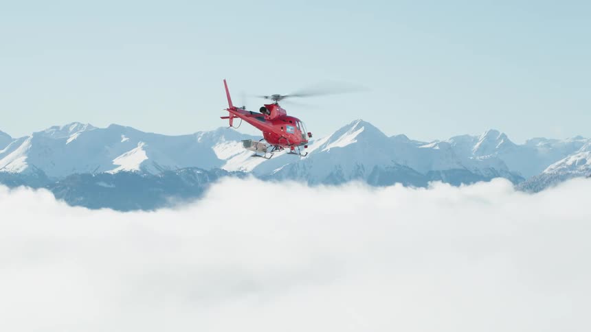 A helicopter flies over the mountains