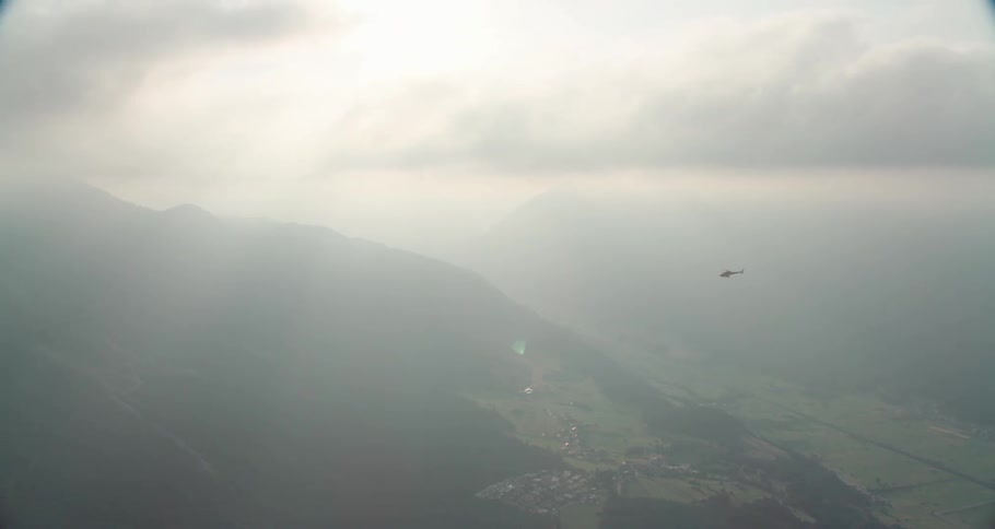 A helicopter flying over a village with the sky in the background