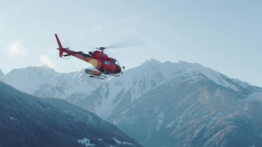 A person flies a helicopter over the mountains