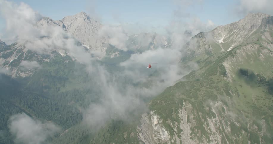 Helicopter flying through mountains in the middle of clouds