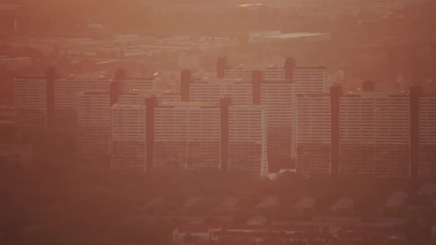 Buildings in city and haze at sunset