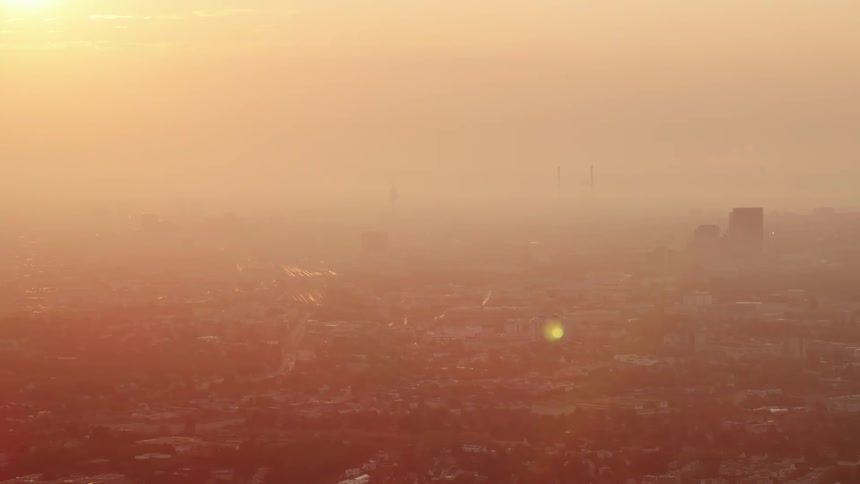 The sound shining through clouds and fog onto a misty city