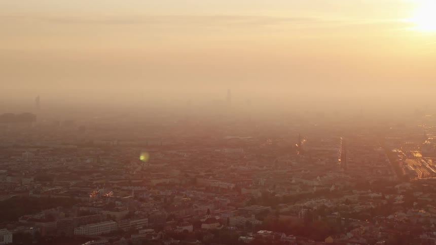 The sun glows and glares in the sky over a city