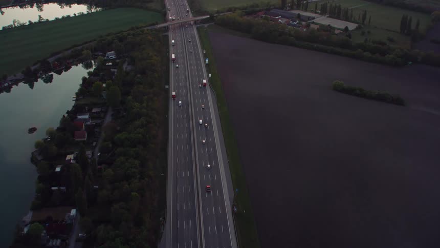An aerial view of cars driving on a freeway alongside a pond