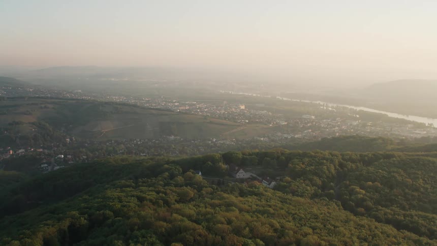 Aerial view of a distant city next to the river at sunset