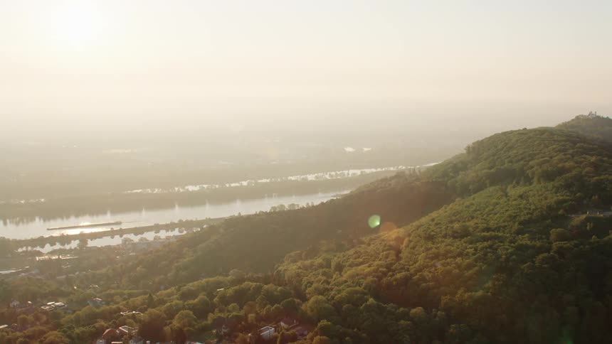 Aerial view of a small town and mountains next to the river at sunset