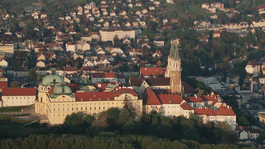 Large building complex surrounded by forest and urban sprawl