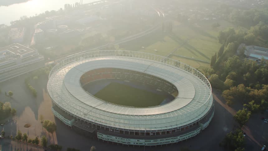 A stadium near a river with grass and trees