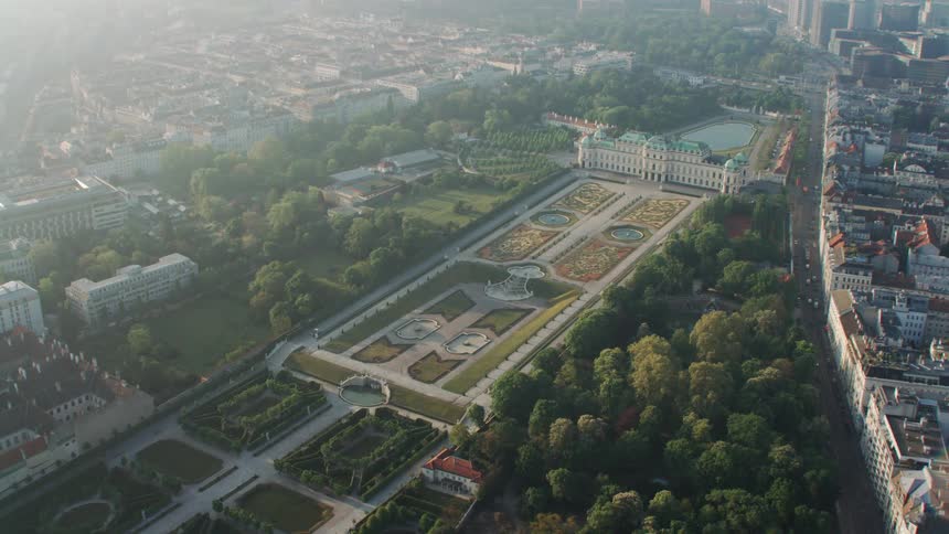 A large courtyard filled with many fountains and gardens in front of a large building