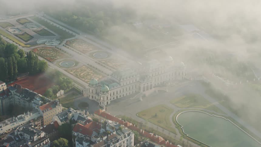 A palace with ornate gardens and landscaping with surrounding city buildings