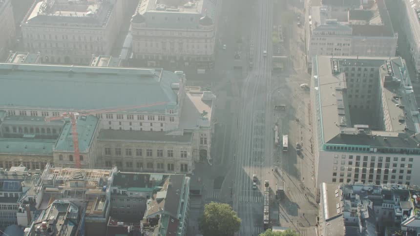 Traffic traveling along a road through a densely packed european city during the day