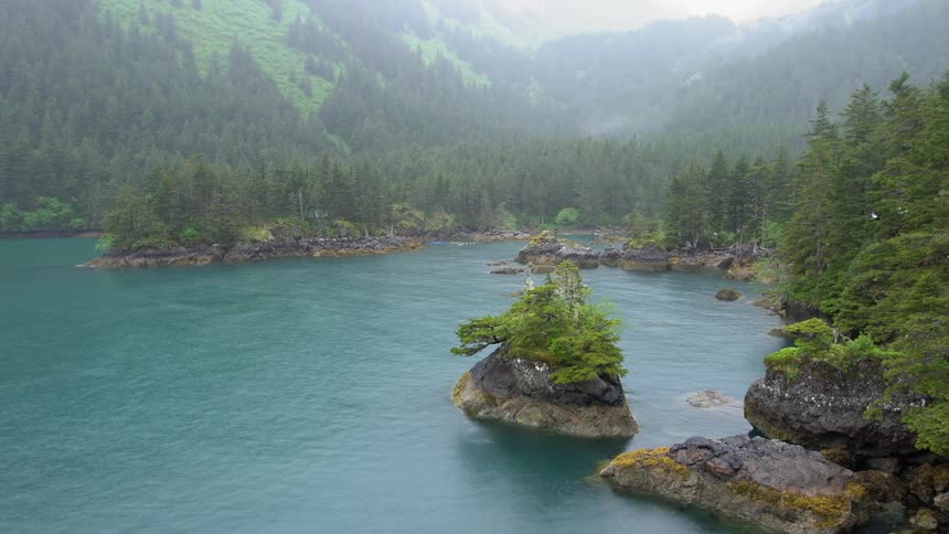 Rain over lake in front of mountains covered in pine tree forest