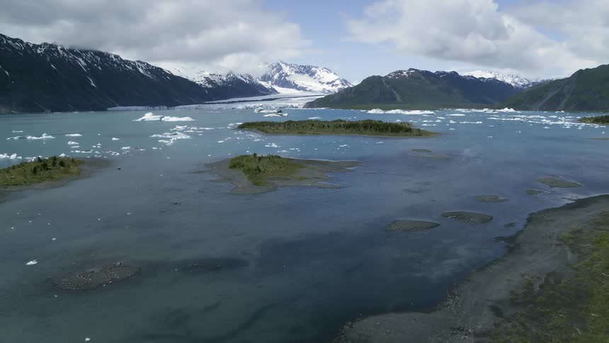 Aerial view of lake in front of glacier between snow covered mountains