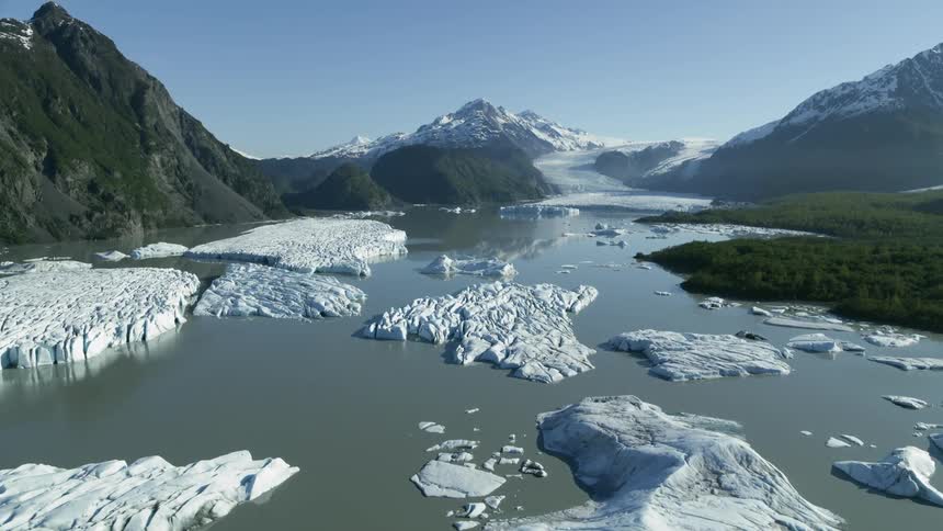 Chunks of ice sit in a large body of water near mountains