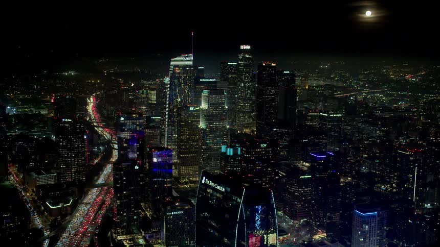 Headlights and taillights glow on a jam packed los angeles highway through the city at night