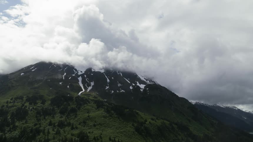 White clouds obscure top of snow covered mountain